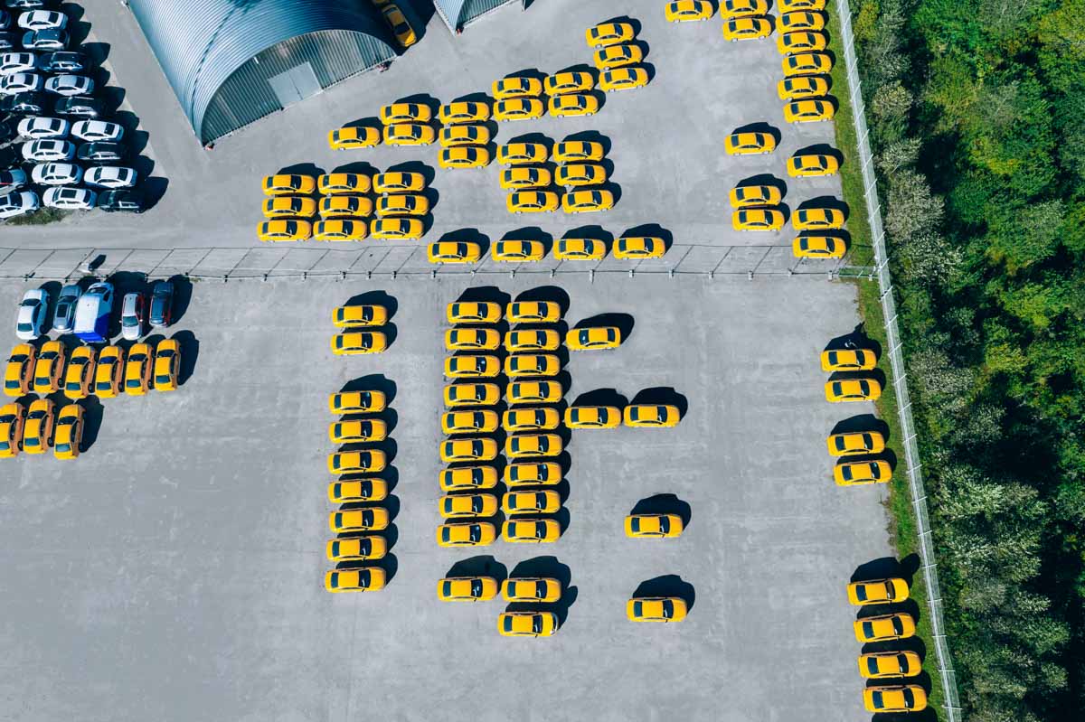 Aerial view of dealership parking lot with many new yellow cars